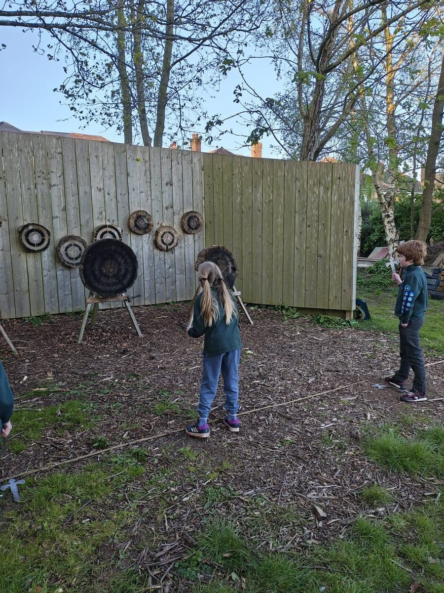 Cubs taking turns axe throwing at wooden targets