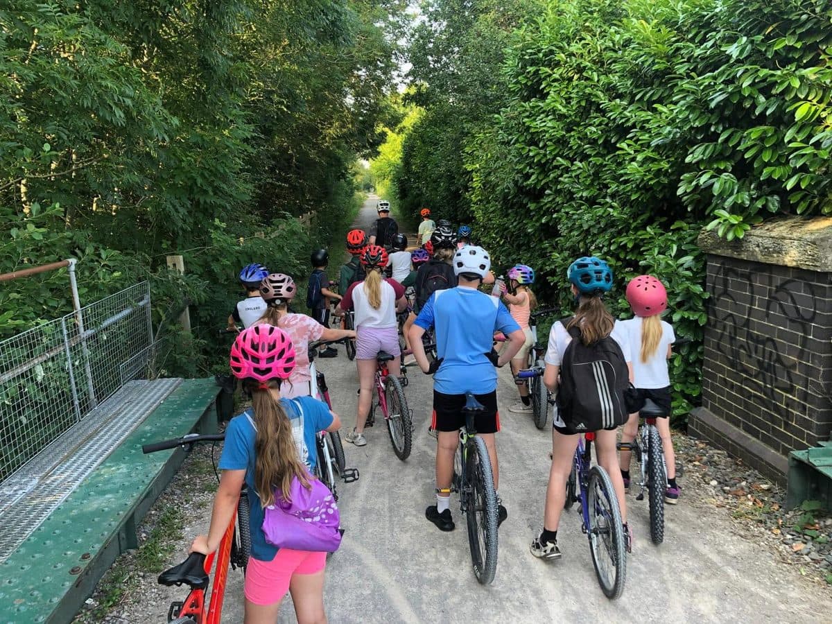 Cubs and leaders pausing on a cycle ride along a tree-lined path