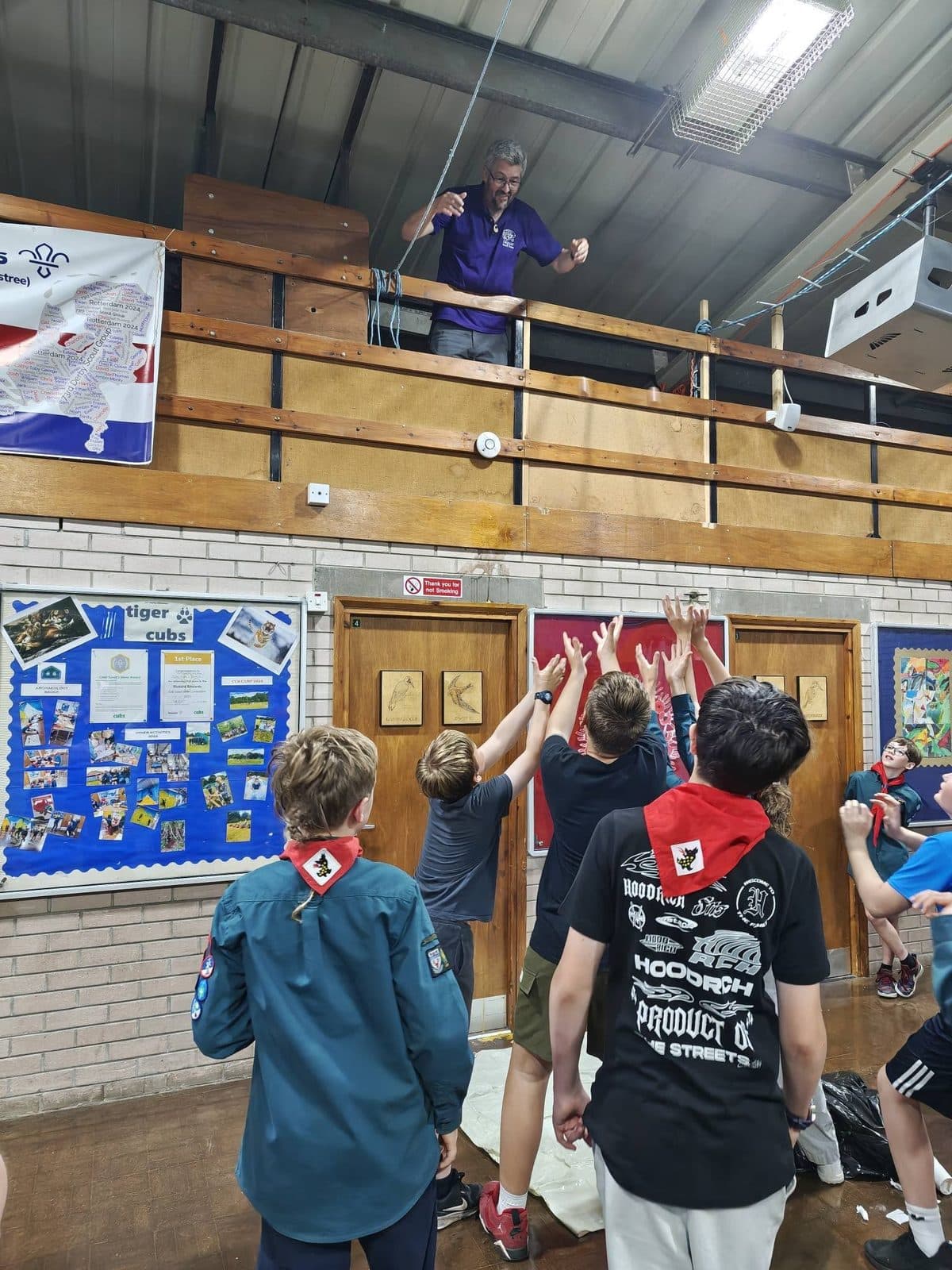 Scouts playing an indoor game, reaching up together